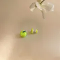Dettaglio macro di orecchini asimmetrici in smalto verde a forma di mela e torsolo - Stile Mela Asimmetrica / Verde