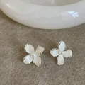 Close-up of elegant flower stud earrings with white enamel petals and pearl center - White