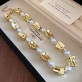 Close-up of vintage pearl necklace with chunky gold-tone links in a jewelry box. - Necklace / Gold/White