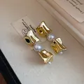 Close-up of vintage gold irregular metal earrings with white pearls in a gift box. - Earrings / Gold/White