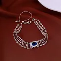 Vista dettagliata di un bracciale vintage in argento con zircone blu su tessuto rosso - Argento-Blu