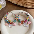 Macro view of colorful beaded hoop earrings featuring delicate butterfly and flower charms - Large / Colorful