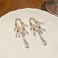 Detalle de pendientes de estilo francés con brillantes diamantes de imitación y cuentas claras - Dorado