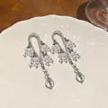 Primer plano de elegantes pendientes de araña plateados con cuentas claras y cristales facetados - Plateado