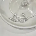 Primo piano di orecchini a stella in argento con zirconi e perle su ceramica bianca - Orecchini a Bottone con Perla e Stella / Argento