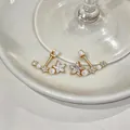 Dettaglio ravvicinato di eleganti orecchini a stella con perle e zirconi - Orecchini a Bottone con Perla e Stella / Oro