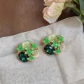 Close-up of elegant forest-style butterfly stud earrings with green enamel and gems. - Silver Needle / Green