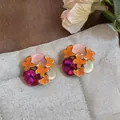 Detailed close-up of vibrant orange butterfly earrings with colorful gemstone accents. - Silver Needle / Orange