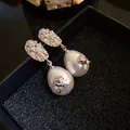 Close-up of French vintage pearl drop earrings with elegant silver flower details - Wrinkled Flower Drop Pearl Stud Earrings / Silver-White
