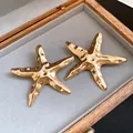 Detaillierte Makroansicht goldener Seestern-Ohrstecker mit gehämmerter Metallstruktur - Seestern Stil (HE33025) / Gold