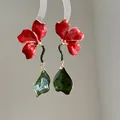 Close-up of red enamel flower earrings with green leaf pendants and glossy finish - Silver Post Gold Tone Red Green