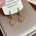 Gros plan de boucles d'oreilles dorées 18 carats avec zircons et turquoise - Or