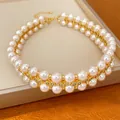 Nahaufnahme der zweireihigen 18 Karat vergoldeten Perlenkette mit glitzernden Zirkonia. - Doppellagige Schlüsselbeinkette / Gold-Rosa