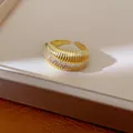 Vista macro dettagliata di anello strutturato placcato oro 14k con pavé di zirconi - Oro