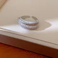 Primo piano di un anello aperto placcato oro 14k con trama e pietre di zircone. - Argento