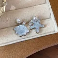 Close-up of asymmetric shell and starfish stud earrings with pearls and blue crushed stone texture - Asymmetric Shell And Star Style / Silver-Blue
