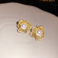 Primer plano detallado de pendientes de flores doradas huecas con perlas y circonitas - Estilo Flor Hueca (HE34149) / Dorado