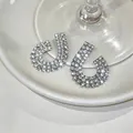 Close-up detail of silver geometric earrings with shimmering rhinestone embellishments. - Silver