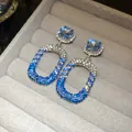 Primo piano di orecchini a pendente in argento con cristalli blu e bianchi su vassoio velluto. - Blu