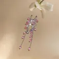 Detailed close-up of silver tassel earrings with pink cat-eye beads and clear zircon stones. - Pink