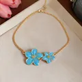 Detailed macro view of a gold chain necklace with blue enamel flower pendants - Gold Necklace / Blue
