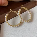 Detailed view of elegant gold plated hoop earrings adorned with small white pearls - Gold