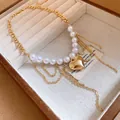 Detailed view of the polished gold heart pendant and white pearls on a vintage chain necklace - Gold