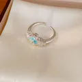 Makro-Detail des blauen Zirkon-Kleeblatt-Designs dieses silberfarbenen offenen Rings - Verstellbarer Offener Stil / Silber-Blau