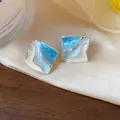 Primo piano di orecchini geometrici ondulati con smalto marmorizzato blu e bianco. - Blu