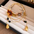 Gros plan d'un collier de perles de style cour vintage avec des fleurs en cristal dorées. - Collier-Brun-Gris