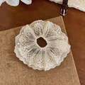 Nahaufnahme eines cremefarbenen Spitzen-Haargummis mit eleganten kleinen weißen Perlen - Haargummi / Weiß