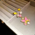 Detailed view of a sweet-style butterfly pendant necklace with pink and yellow enamel charms - Necklace (HN12099)