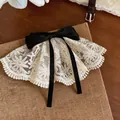 Detailansicht einer eleganten cremefarbenen Haarklammer aus Spitze mit einer schwarzen Schleife. - Federclips / Weiß-Schwarz