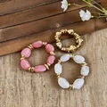 Drei stilvolle geometrische Acryl-Armbänder mit goldfarbenen Akzenten auf rustikalem Grund. - 3er-Set (S/M/L) / Rosa und Transparent