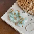 Detailed view of mint green petal drop earrings with gold bar tassels on vintage book - Purple (Ear Clip)