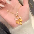 Detail view of 24k gold plated necklace featuring zircon flowers and matte bow charm - Gold