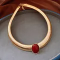 Primo piano di una collana vintage dorata a spirale con grande resina rossa ovale - Oro-Rosso