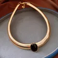 Primo piano di collana vintage dorata a lisca di pesce con cabochon ovale in resina nera. - Oro-Nero