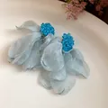 Detailed view of light blue chiffon flower tassel earrings with beaded studs - Blue