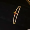 Gros plan sur un bracelet plaqué or à double rangée avec un charm de fleur en zircons - Style Zircone Coloré / Or