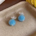 Macro view of blue glass flower textured round drop earrings on tray - Hook Style / Blue