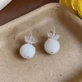 Detail shot showing elegant white frosted glass ball pendant earrings with silver hooks - Hook Style / White