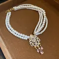 Dettaglio squisito della collana di perle a più fili con ciondolo floreale rosa - Multistrato (Oro-Bianco-Rosa)