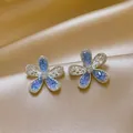 Close-up of elegant blue hollow-out flower stud earrings with sparkling crystals and pearls - Hollow Flower Style (HE32171-) / 1 Pair Pack / Blue-Silver