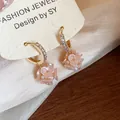 Close-up of elegant gold hoop earrings with zircon stones and pink flower charms - Hoop Style / Gold Pink