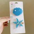 Detailed view of exquisite blue starfish and shell hair clips with a pearlescent finish - Starfish Scallop Duckbill Clip / Two-Piece Set / Blue