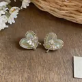 Close-up of heart-shaped earrings with butterfly pearl details on wooden background - Butterfly Heart Pearl Style / Silver