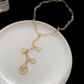 Detailed view of a gold link chain necklace with multiple portrait-engraved coin charms. - Gold