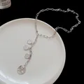 Macro detail of a silver Y-shape necklace with four round portrait coin pendants. - Silver