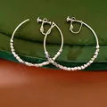 Close-up of faceted metal beads and screw-back mechanism on silver hoop earrings - Clip-On Earrings / Silver